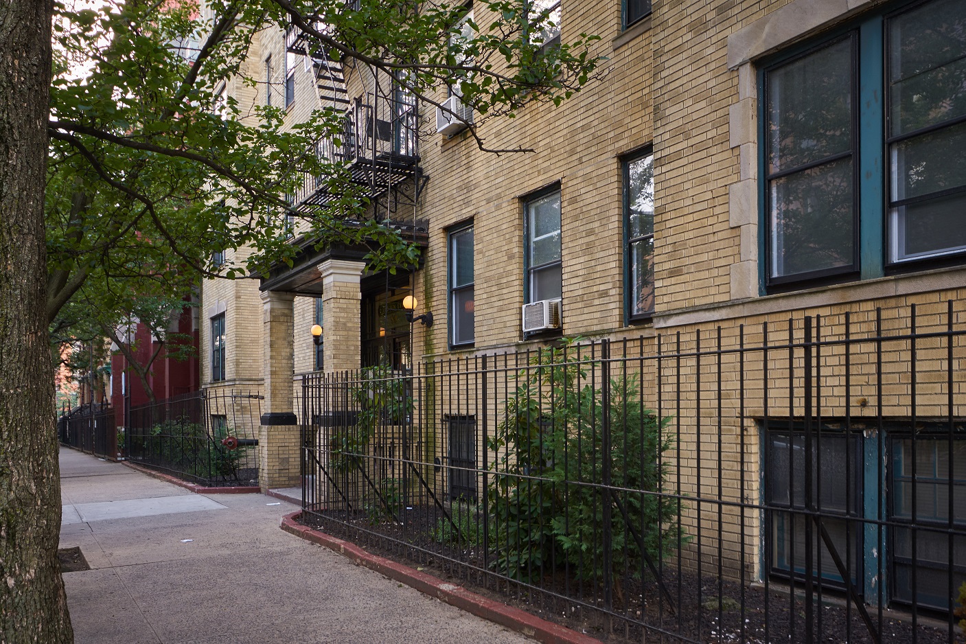 A row of brown brick buildings with green plants growing on the side.